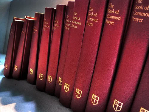 A shelf of oxblood Books of Common Prayer